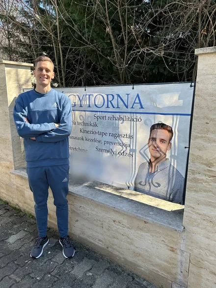 Wettstein Gergely gyógytornász mosolyogva a szabadban, a gyógytorna-molinója mellett